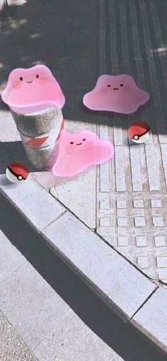 two pink cups with faces on them are sitting on the sidewalk next to each other