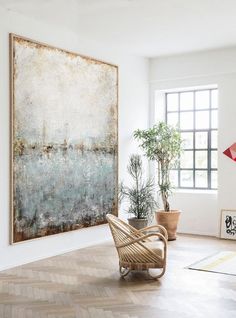 a painting hanging on the wall next to a chair and potted plant