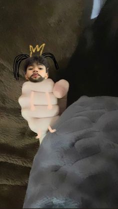 a small child wearing a crown and holding onto a stuffed animal in a fake bed