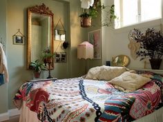 a bed sitting in a bedroom next to a mirror and potted plant on the wall