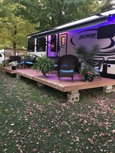 an rv is lit up with purple lights in the back yard and decking area