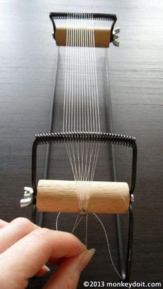 a person is holding a string with a wooden spool attached to it and the strings are being pulled through