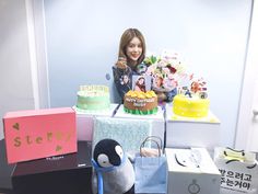 a woman standing behind a table with cakes and gifts