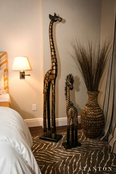 two giraffes are standing next to each other near a lamp and bed