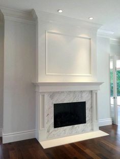 an empty living room with a fireplace and white paint on the walls, wood flooring