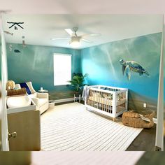 a baby's room decorated in blue and white with a turtle painted on the wall