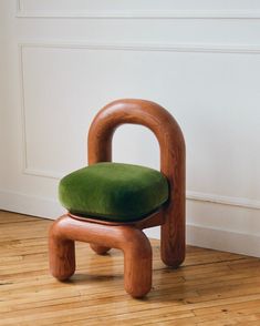 a wooden chair sitting on top of a hard wood floor next to a white wall