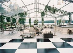 a room with black and white checkered flooring, chandeliers and tables