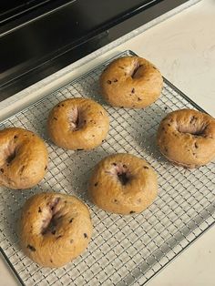 six doughnuts sitting on a cooling rack in front of an oven door, ready to be baked