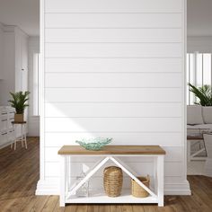 a room with white walls and wooden flooring has a table on one side, two baskets on the other