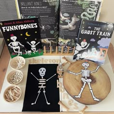 children's books and crafts are displayed on a wooden table with skeleton figurines