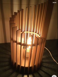 a light that is sitting on top of a table next to a lamp shade with wooden strips