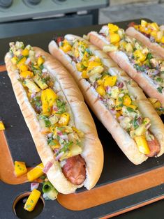 three hot dogs with toppings sitting on a tray