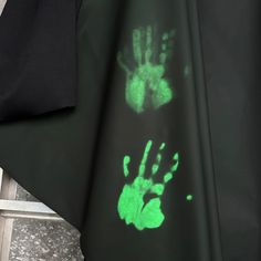 a green hand print on the side of a black sheet with white writing underneath it