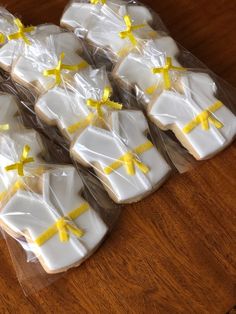 some cookies are wrapped in plastic and have yellow bows on them, sitting on a wooden table