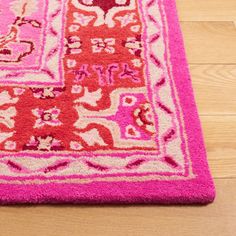 a pink and red rug sitting on top of a wooden floor