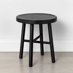 a black stool against a white wall