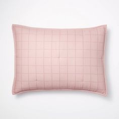 a pink pillow on a white wall with a black and white checkered pattern in the middle