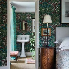 a bedroom with green floral wallpaper and a white pedestal sink