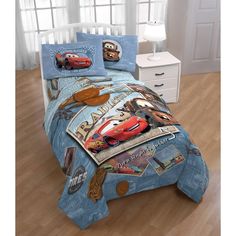 a bed with cars comforter and pillows on it