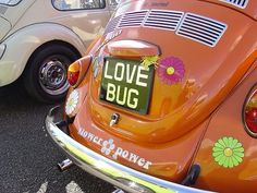 an orange vw bug parked in a parking lot next to other old volkswagen cars