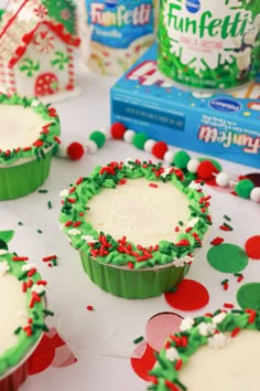 christmas cupcakes with frosting and sprinkles on a white table