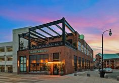 an empty street in front of a large brick building with the sun setting on it