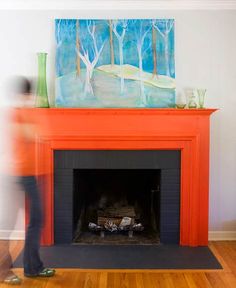 a person standing in front of a fireplace with a painting on the wall above it