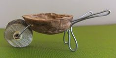 a small wooden bowl with metal handles on a green surface