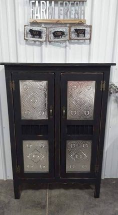 a black cabinet with two glass doors and metal handles on the door is sitting in front of a sign that says farm fresh