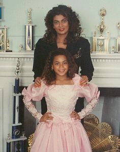 two women standing next to each other in front of a fireplace