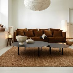 a living room with a couch, coffee table and vases on the floor in front of it