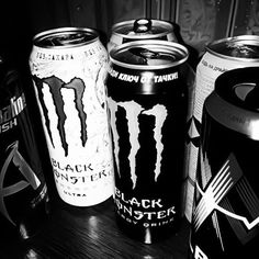 black monster energy drinks are lined up on a table in this black and white photo