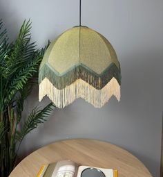 an open book sitting on top of a wooden table next to a green lamp shade