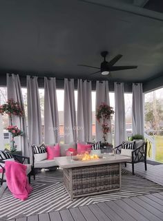 an outdoor living room with white curtains and pink pillows