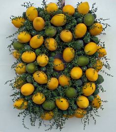 an arrangement of lemons and limes arranged in the shape of a wreath on a white wall