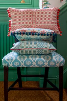 four pillows stacked on top of each other in front of a green wall and chair