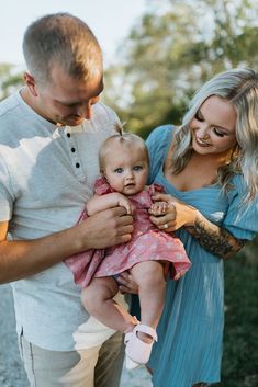 a man and woman holding a baby in their arms