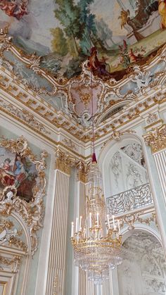 a chandelier hanging from the ceiling in a room with paintings on the walls