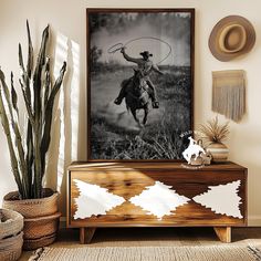 a black and white photo of a man on a horse with a lasso in his hand