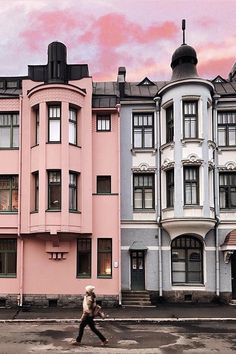 a person walking down the street in front of some colorful buildings on a cloudy day