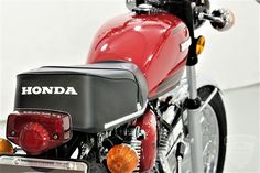 a red motorcycle parked in a garage next to a white wall with the words honda on it