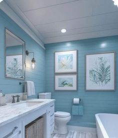 a bathroom with blue walls and white fixtures, including a tub, sink, toilet and mirror