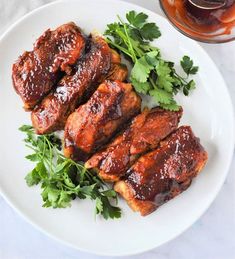 meat with sauce and parsley on a white plate next to a jar of ketchup