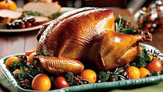 a roasted turkey on a platter with oranges and other holiday foods around it