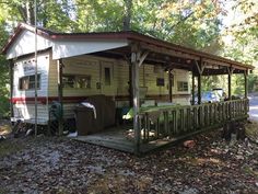 a mobile home sits in the woods next to a picnic table and grilling area