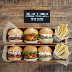 several sandwiches and fries are on display in two wooden trays, with the sign for the coffeehouse brooklyn coffee and tea