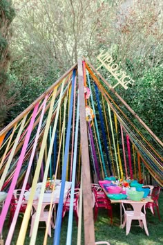 an outdoor party with colorful sticks and plates on the table in front of a teepee