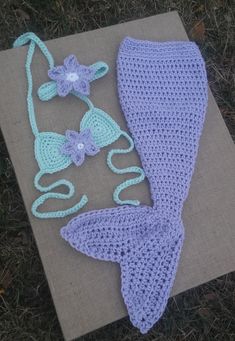 a crocheted mermaid tail, diaper and headband are laying on the ground