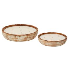 two white candles in wooden bowls on a white background